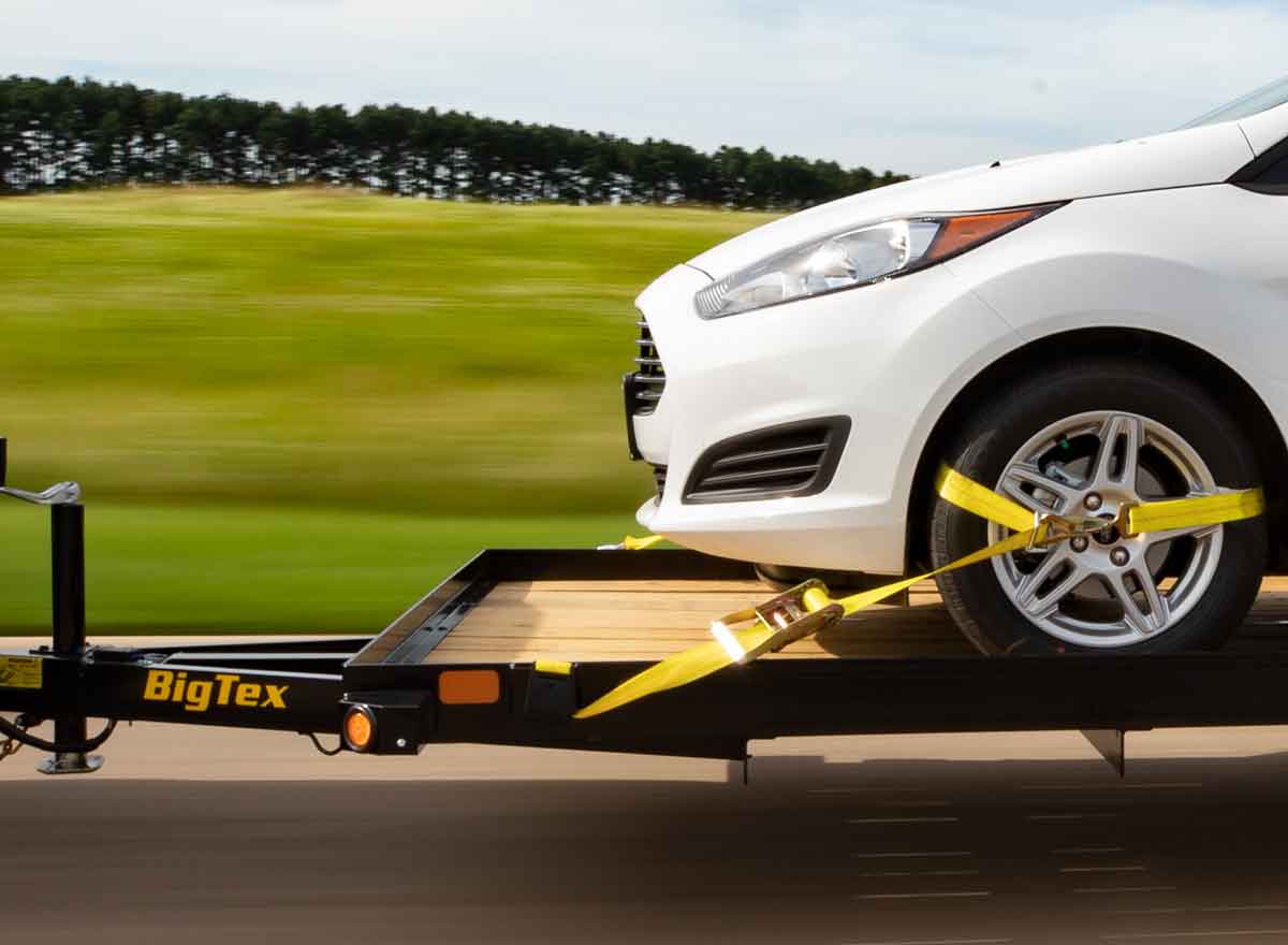 white car secured onto a Big Tex trailer with yellow straps