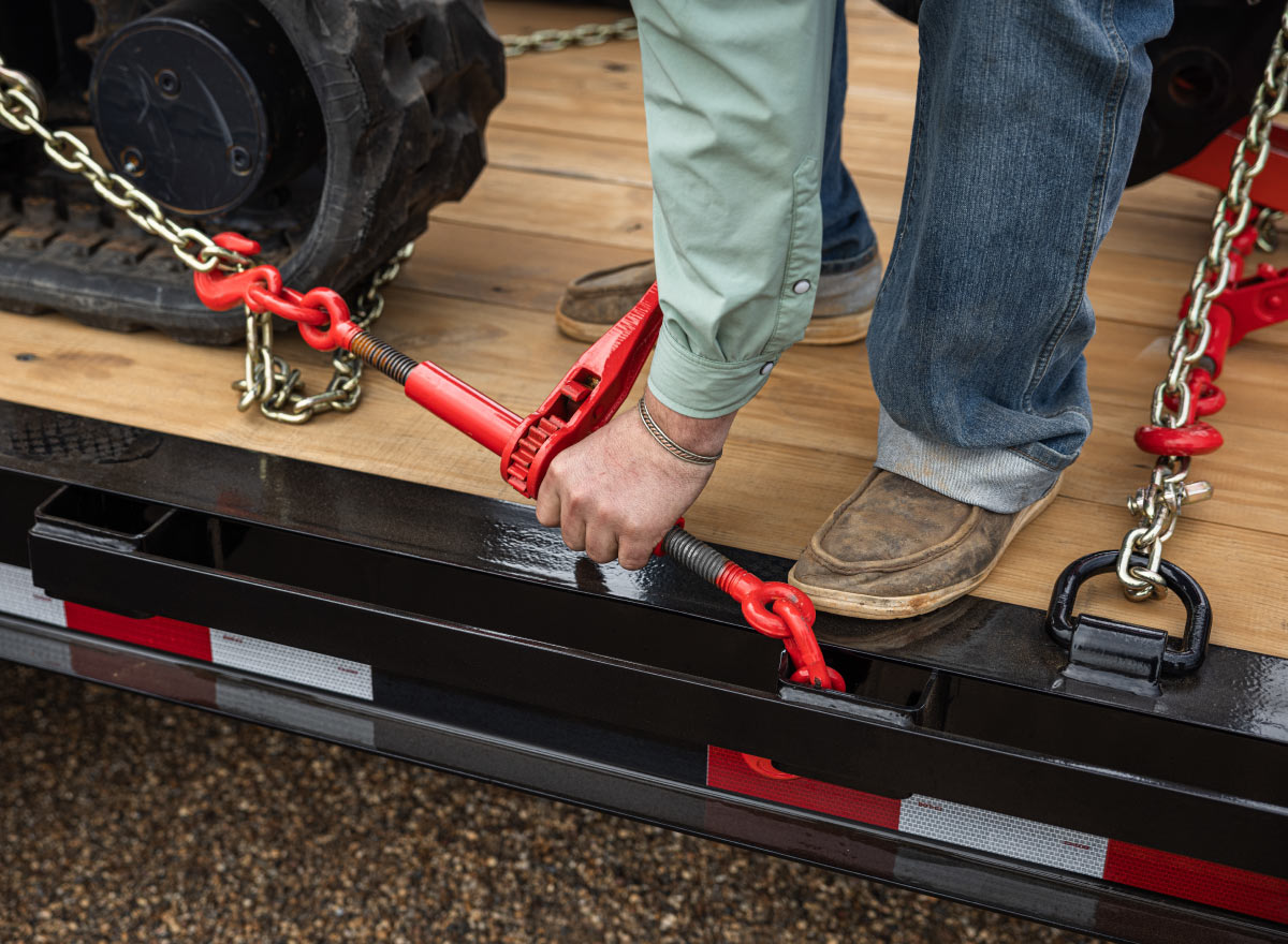 man is attaching chains to a trailer